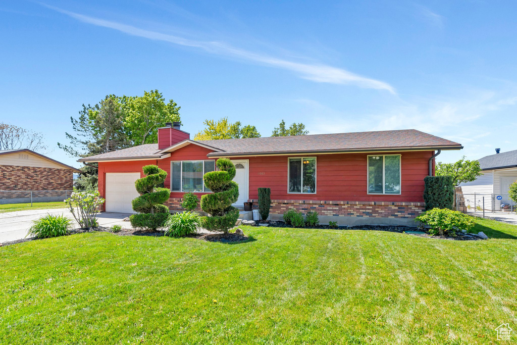 Ranch-style house with a garage, a chimney, driveway, brick siding, and roof with shingles