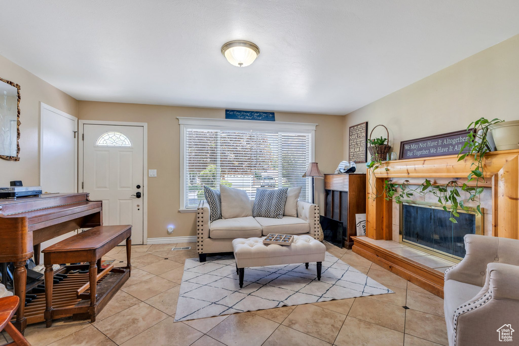 Living room with a premium fireplace, healthy amount of natural light, light tile patterned flooring, and baseboards