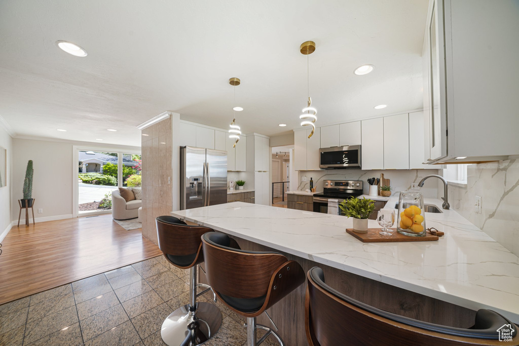 Kitchen featuring appliances with stainless steel finishes, a sink, a peninsula, recessed lighting, and decorative backsplash