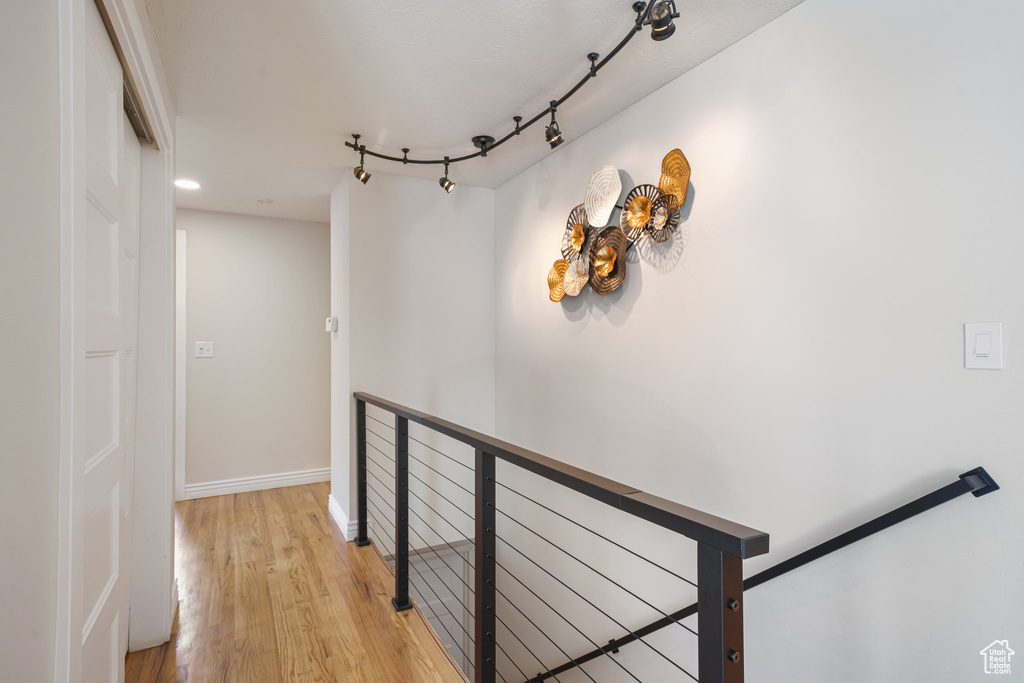 Hallway with an upstairs landing, light wood-style floors, and baseboards