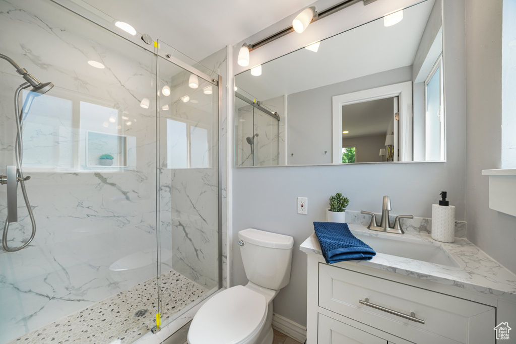 Bathroom with vanity, toilet, and a marble finish shower