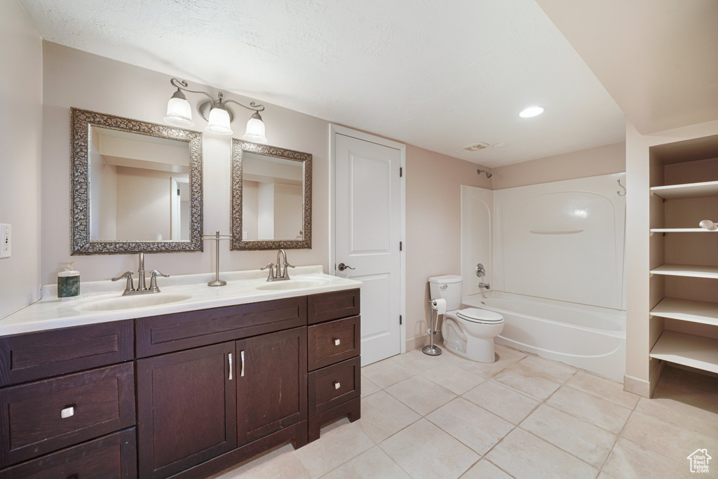 Bathroom with double vanity, toilet, tile patterned flooring, recessed lighting, and baseboards