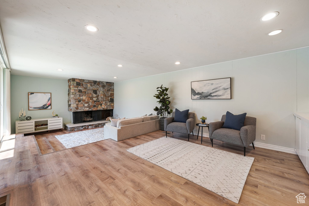 Living area with a stone fireplace, recessed lighting, wood finished floors, and baseboards