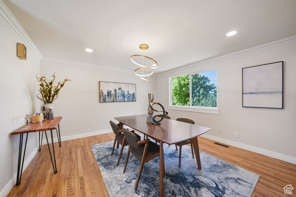 Dining space featuring crown molding, light wood-style flooring, baseboards, and recessed lighting