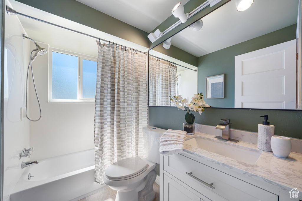 Full bath with vanity, shower / tub combo with curtain, and toilet