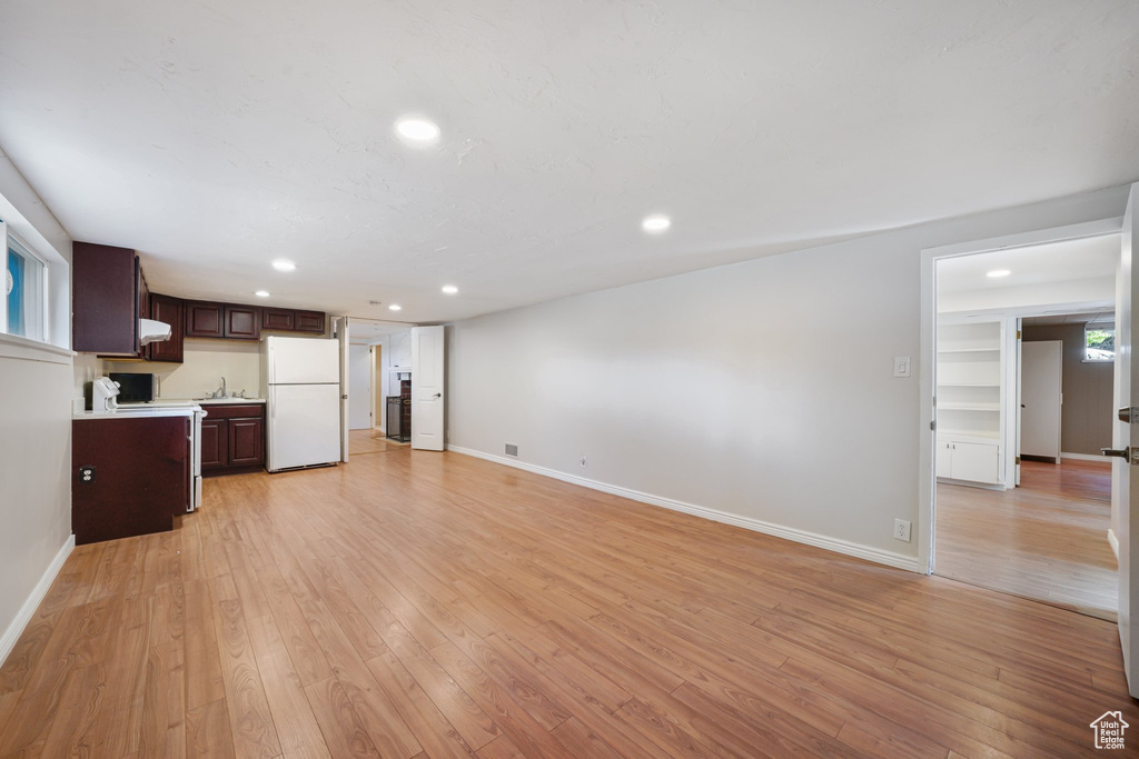 Unfurnished living room featuring a sink, recessed lighting, baseboards, and light wood-style flooring