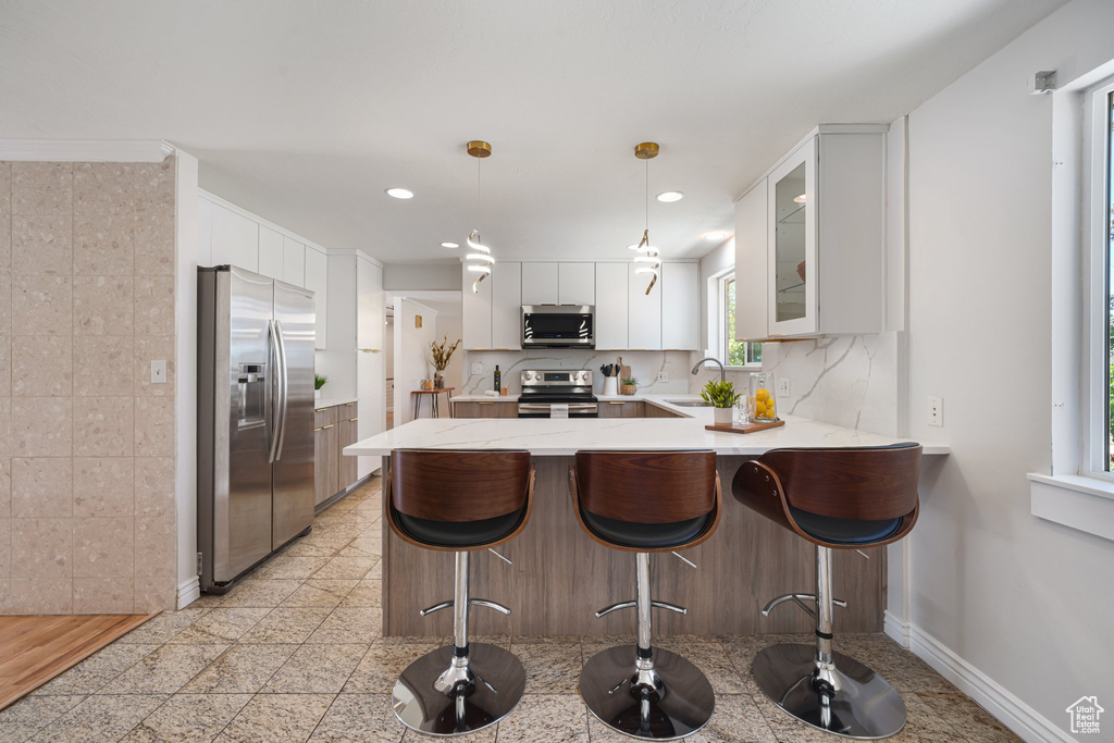 Kitchen featuring stainless steel appliances, a peninsula, a sink, glass insert cabinets, and recessed lighting