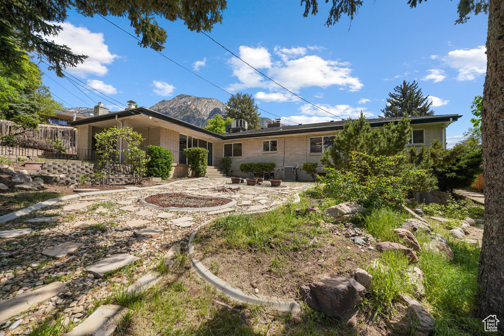 Back of property with brick siding, a mountain view, and a chimney