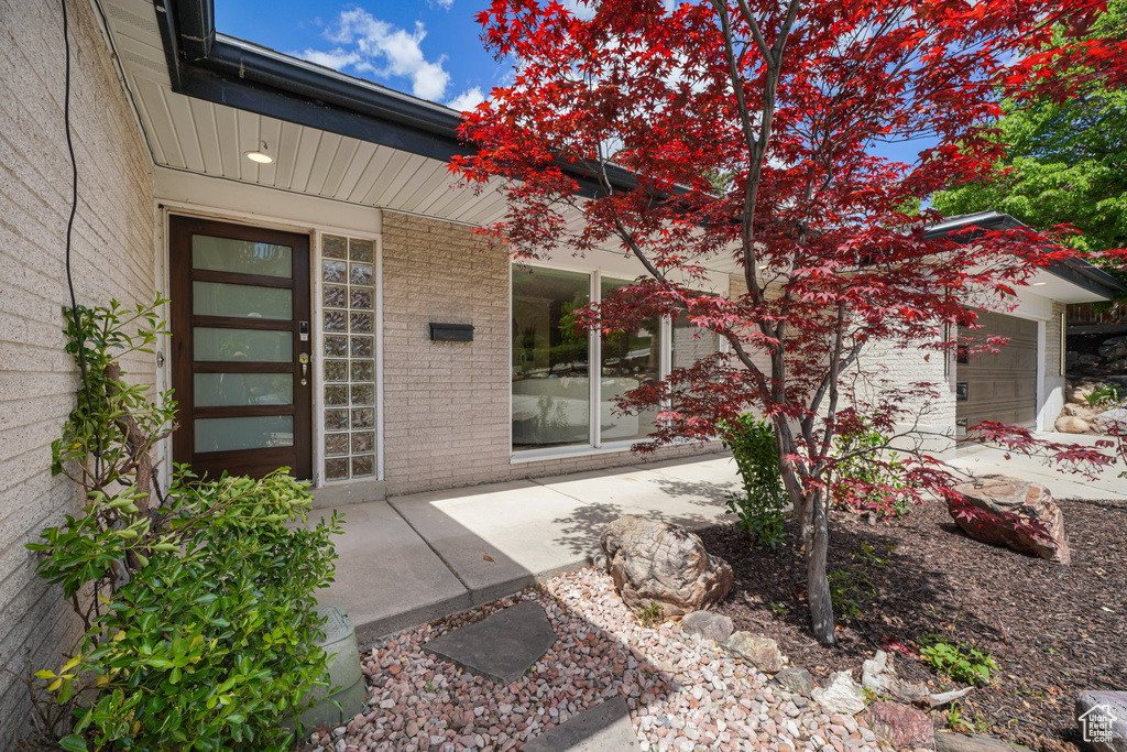 Entrance to property with brick siding, a garage, and a porch
