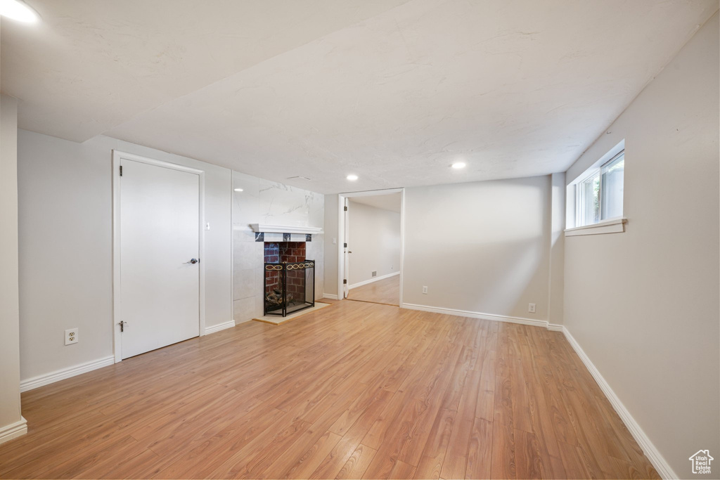 Unfurnished living room featuring a tile fireplace, light wood-style floors, baseboards, and recessed lighting