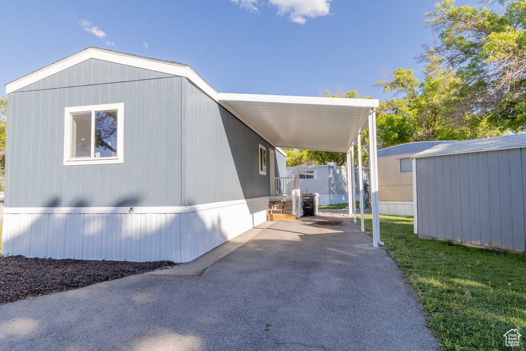 View of side of home featuring an outbuilding, a storage unit, a carport, and driveway