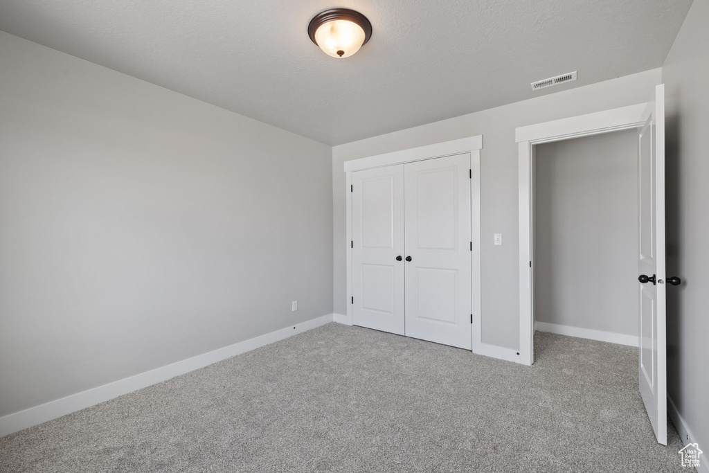 Unfurnished bedroom featuring carpet floors, baseboards, and a closet