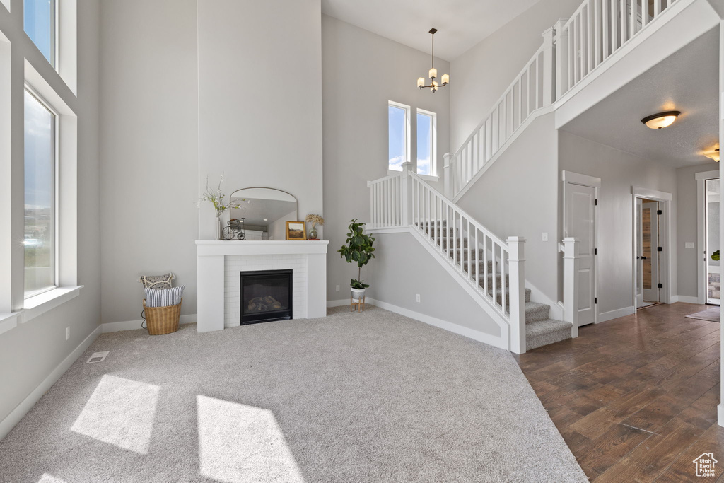 Living room featuring a high ceiling, stairway, a glass covered fireplace, a chandelier, and baseboards