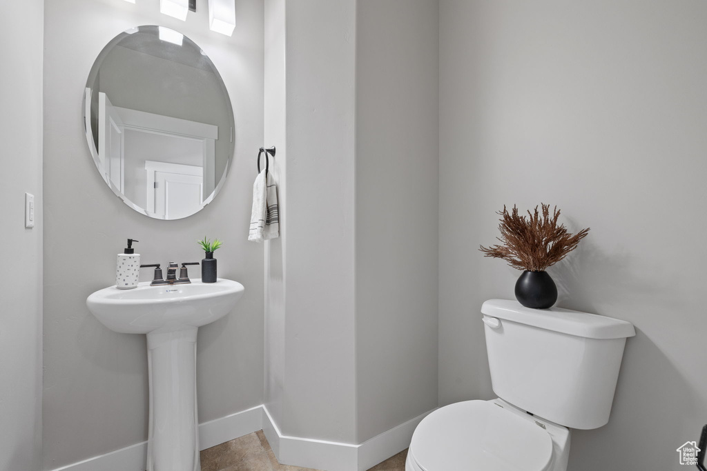Bathroom featuring toilet, baseboards, and a sink