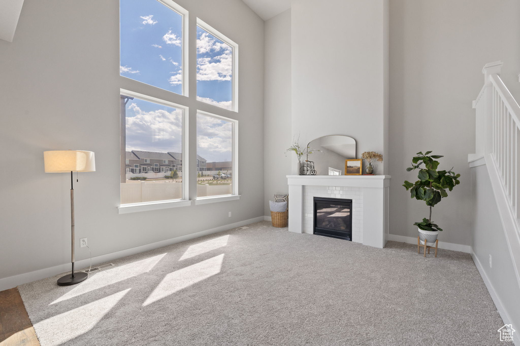 Living room featuring plenty of natural light, carpet floors, a glass covered fireplace, and a towering ceiling