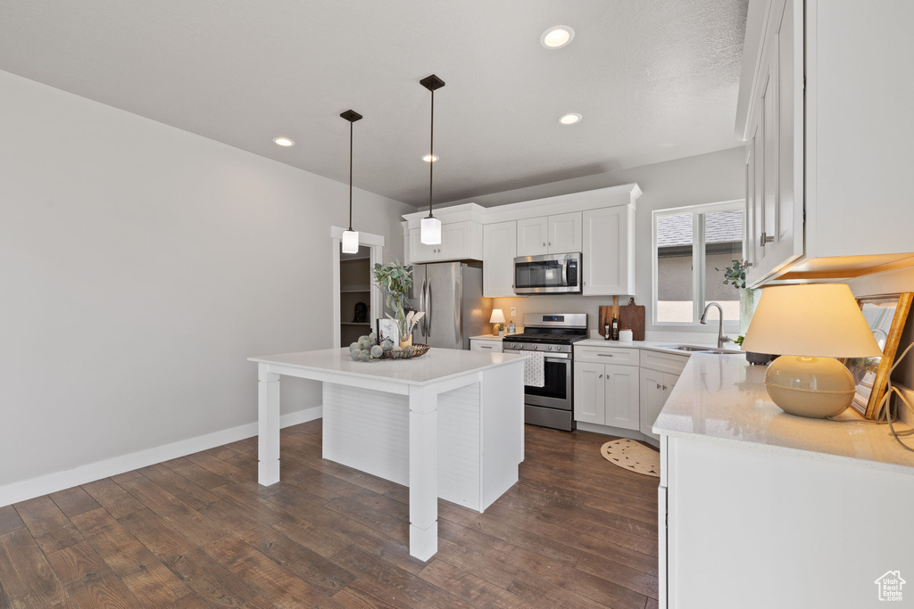 Kitchen featuring stainless steel appliances, a sink, a kitchen bar, white cabinetry, and a center island