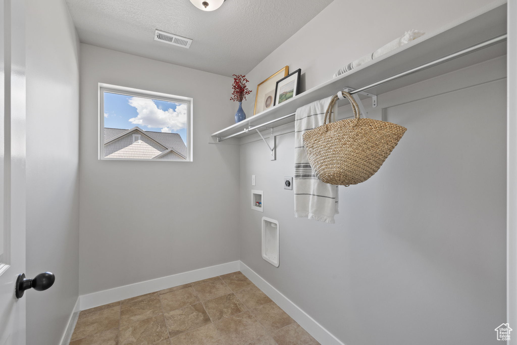 Washroom with hookup for an electric dryer, baseboards, hookup for a washing machine, and a textured ceiling
