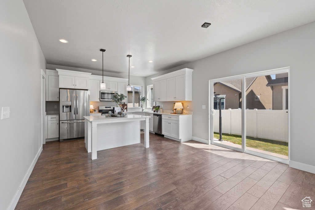 Kitchen with appliances with stainless steel finishes, dark wood-style flooring, white cabinets, recessed lighting, and baseboards