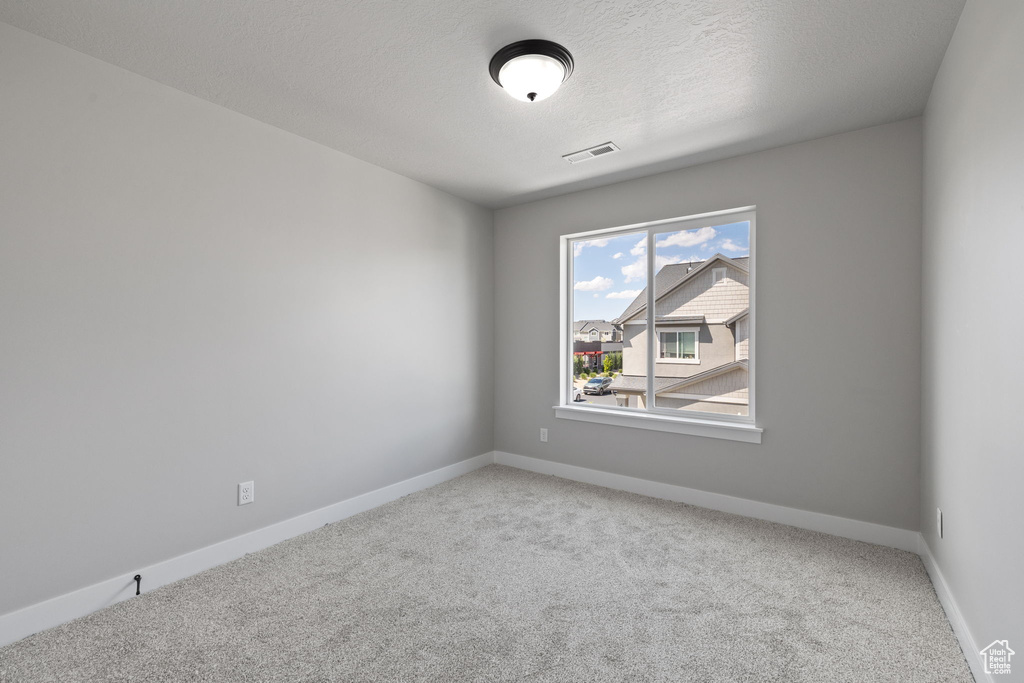 Carpeted spare room with baseboards and a textured ceiling