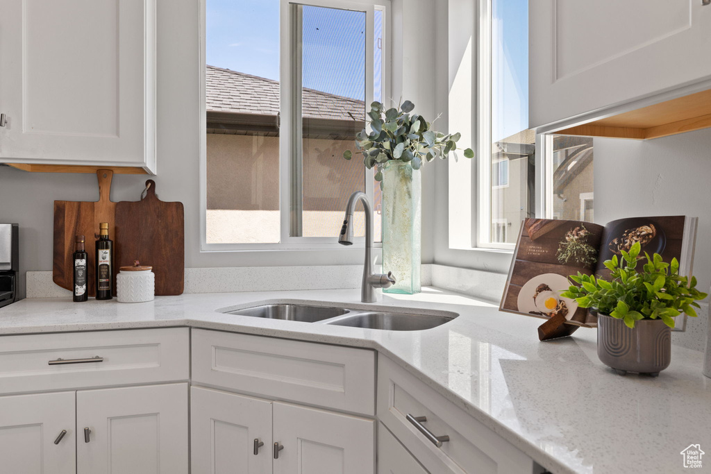 Kitchen with a sink, plenty of natural light, and white cabinetry