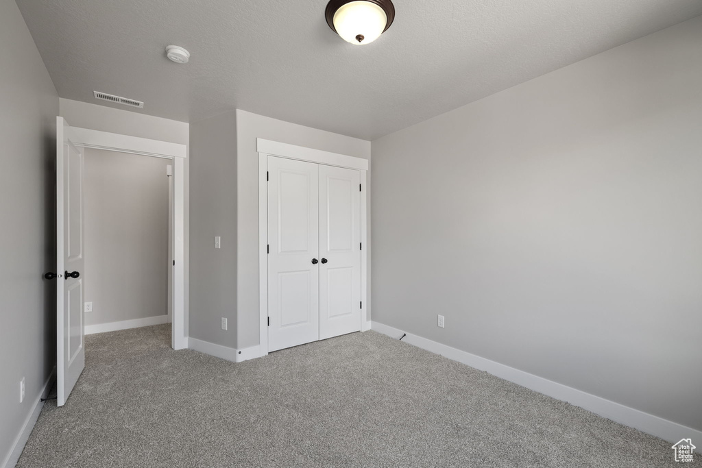 Unfurnished bedroom featuring carpet floors, baseboards, and a closet