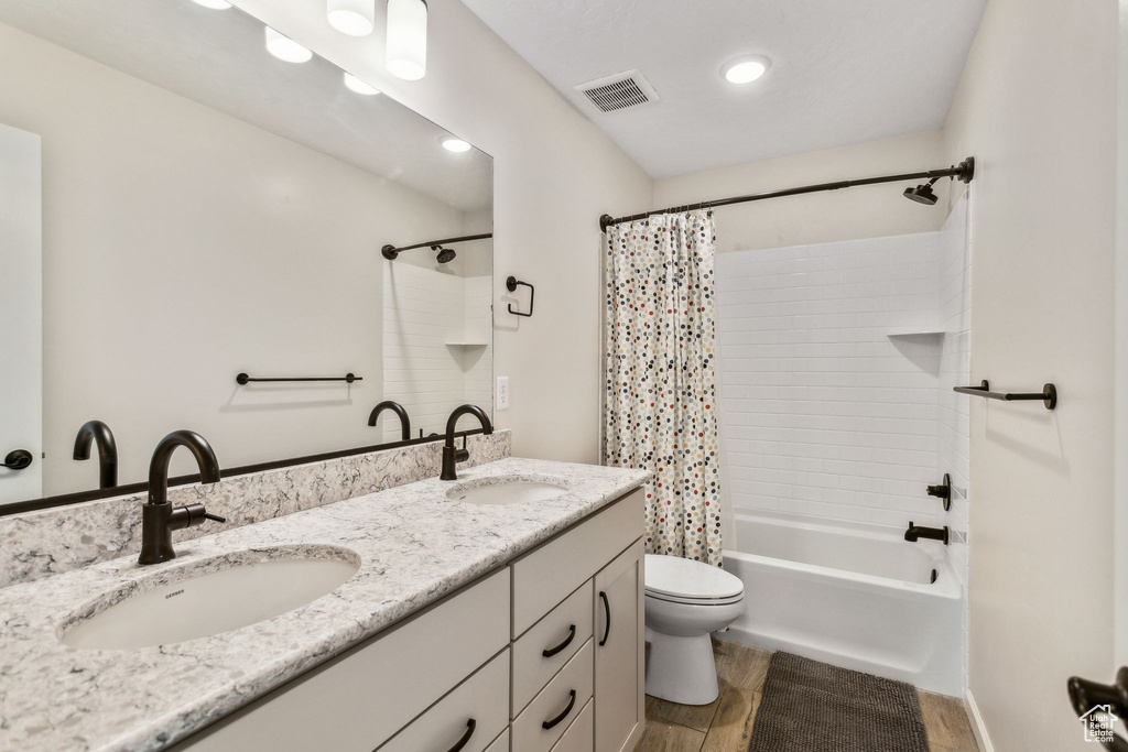 Bathroom with toilet, shower / bath combination with curtain, and double vanity