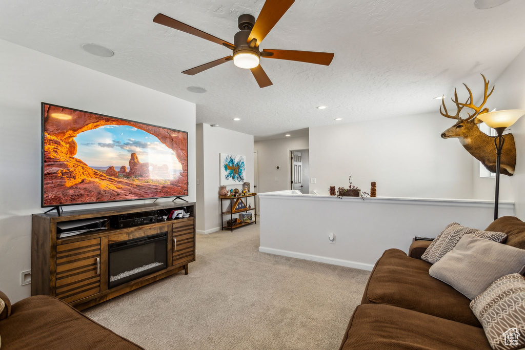 Living area with ceiling fan, light carpet, recessed lighting, baseboards, and a textured ceiling