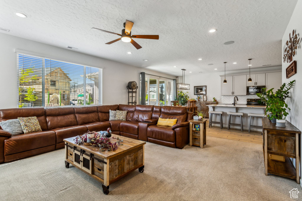 Living area with plenty of natural light, ceiling fan, a textured ceiling, recessed lighting, and light carpet