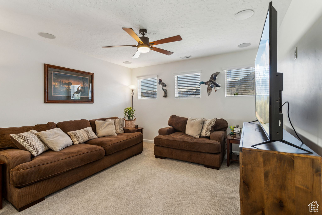 Living room with light colored carpet, a ceiling fan, and a textured ceiling