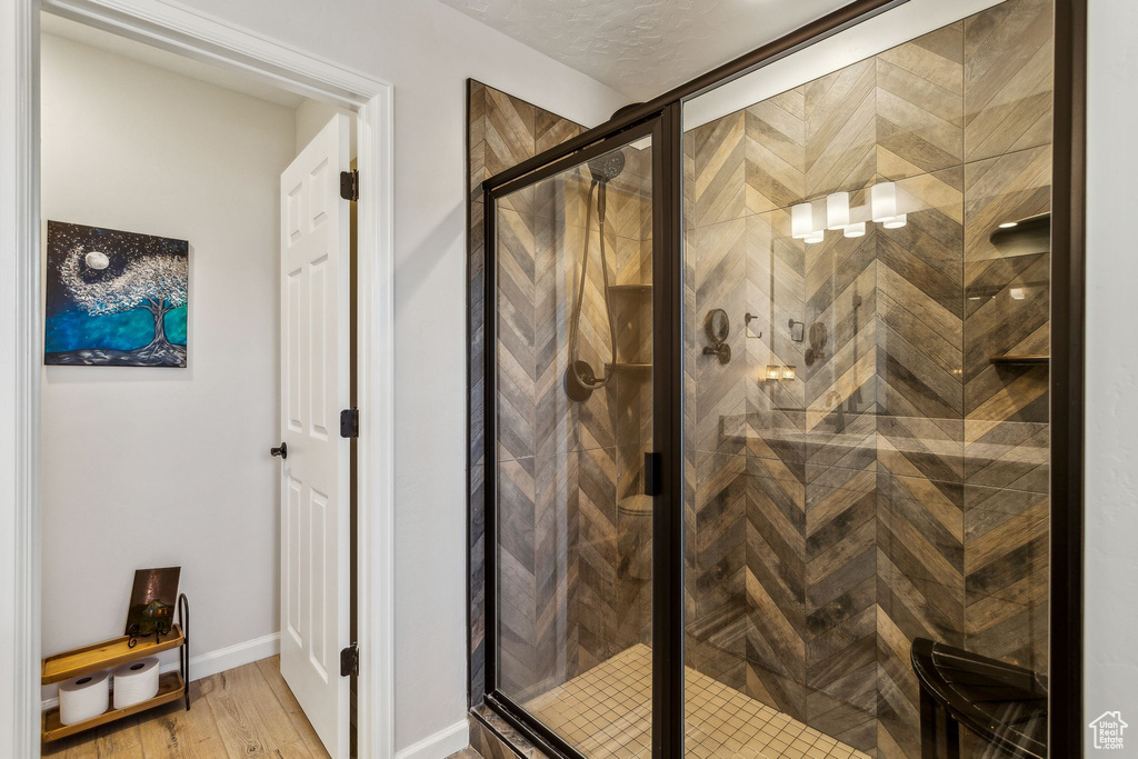 Full bathroom with wood finished floors, a shower stall, and baseboards