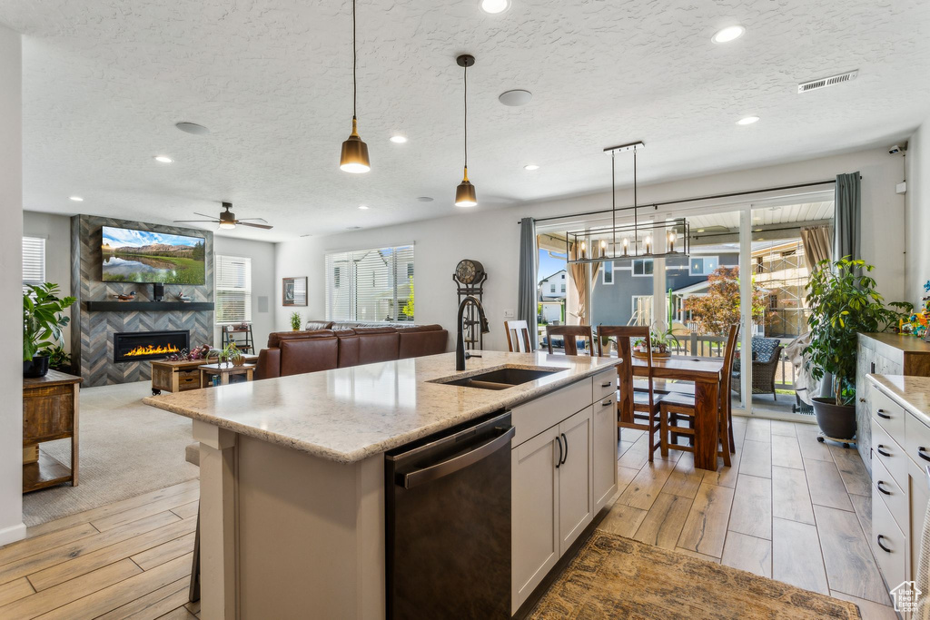Kitchen with dishwasher, a sink, ceiling fan, white cabinets, and a textured ceiling