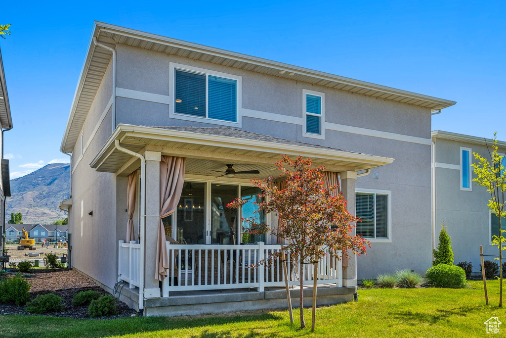 View of front of home featuring a porch, a ceiling fan, stucco siding, and a front yard