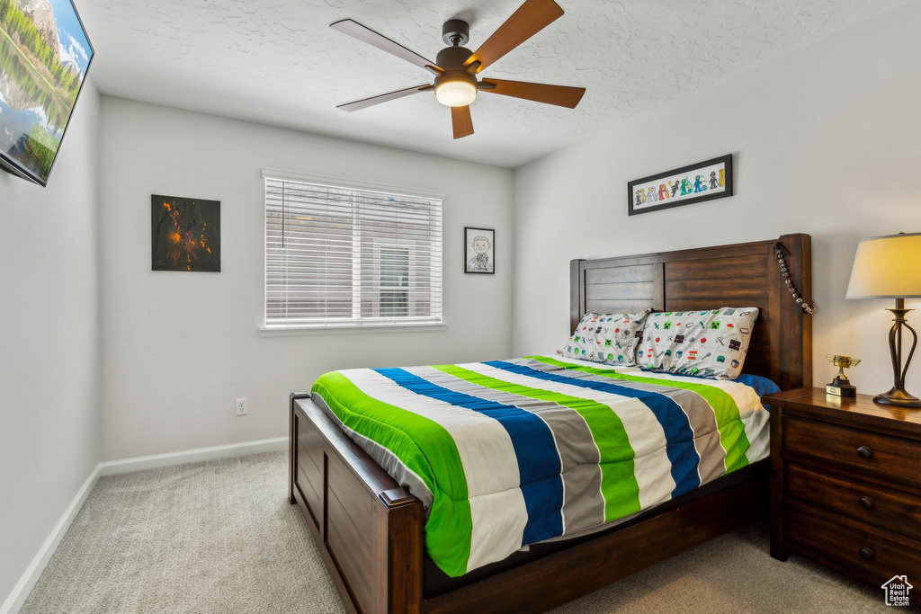 Bedroom with carpet flooring, baseboards, a textured ceiling, and a ceiling fan