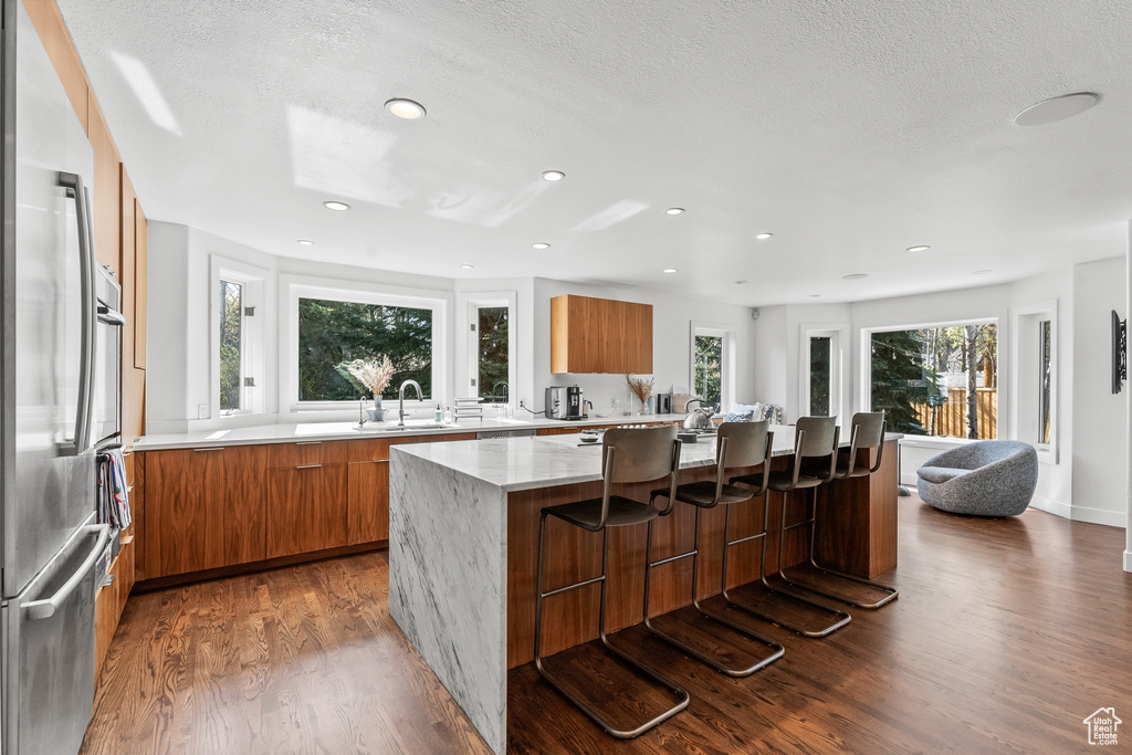 Kitchen featuring modern cabinets, a sink, wood finished floors, brown cabinetry, and recessed lighting