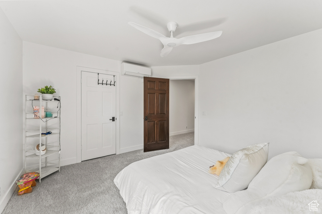 Carpeted bedroom featuring an AC wall unit, baseboards, and ceiling fan
