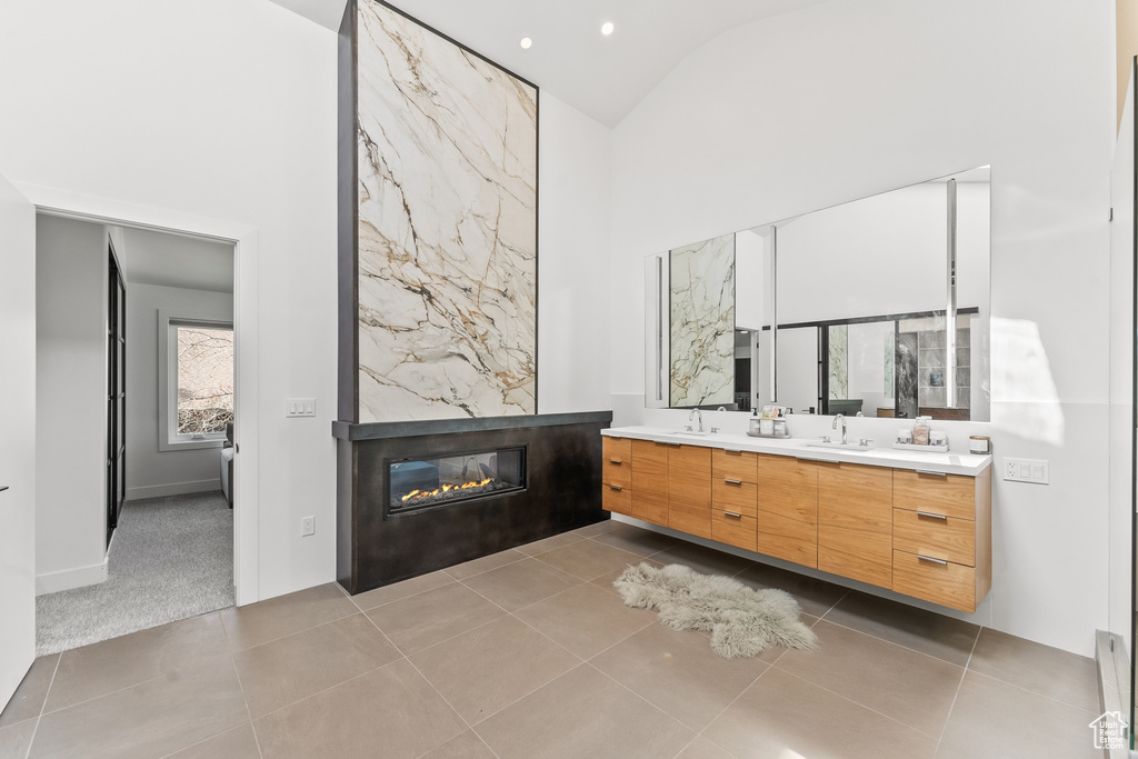 Full bathroom with high vaulted ceiling, double vanity, a fireplace, tile patterned flooring, and recessed lighting