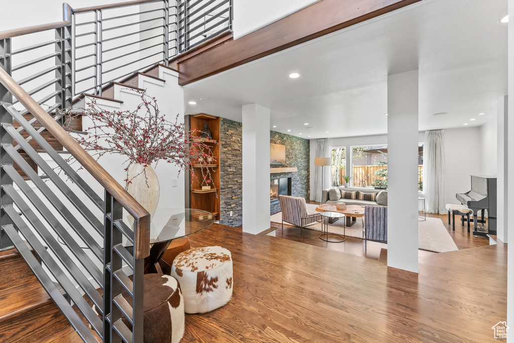 Staircase with wood finished floors, a stone fireplace, and recessed lighting