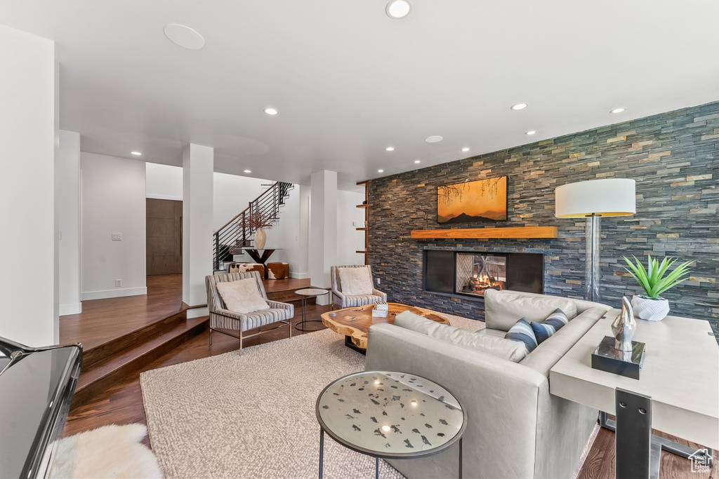 Living area with stairs, a stone fireplace, wood finished floors, recessed lighting, and baseboards