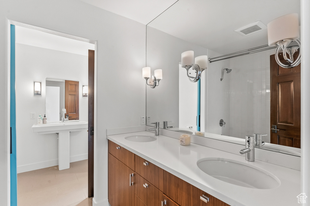 Bathroom featuring a shower, dual sinks, and baseboards