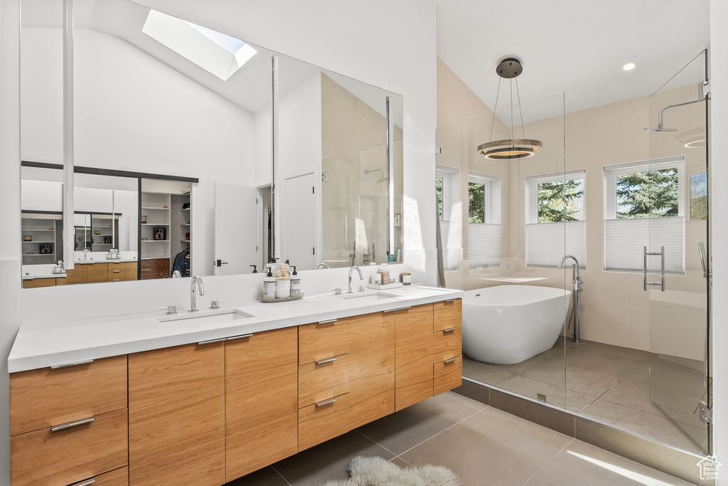 Bathroom with a shower stall, healthy amount of natural light, a skylight, double vanity, and high vaulted ceiling