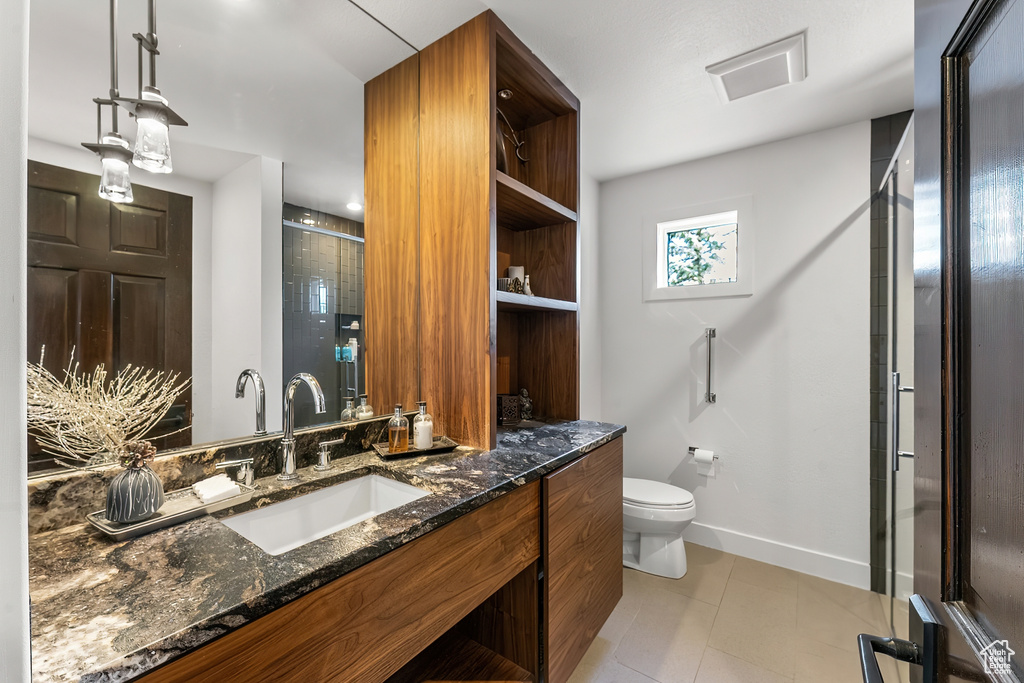 Full bathroom featuring toilet, tile patterned flooring, baseboards, vanity, and a shower with shower door