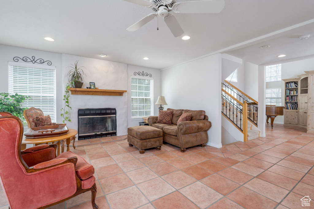 Living room featuring stairs, a ceiling fan, a glass covered fireplace, recessed lighting, and baseboards