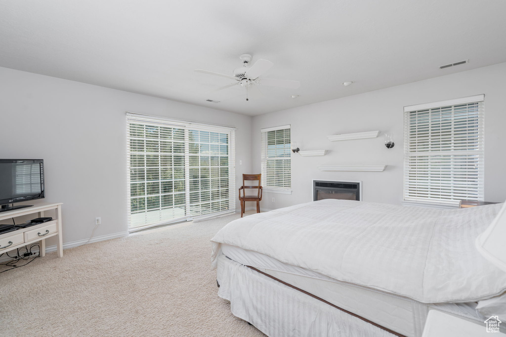 Bedroom featuring baseboards, carpet, a ceiling fan, and a glass covered fireplace