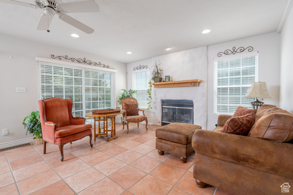 Living area featuring a glass covered fireplace, recessed lighting, light tile patterned floors, a ceiling fan, and baseboards