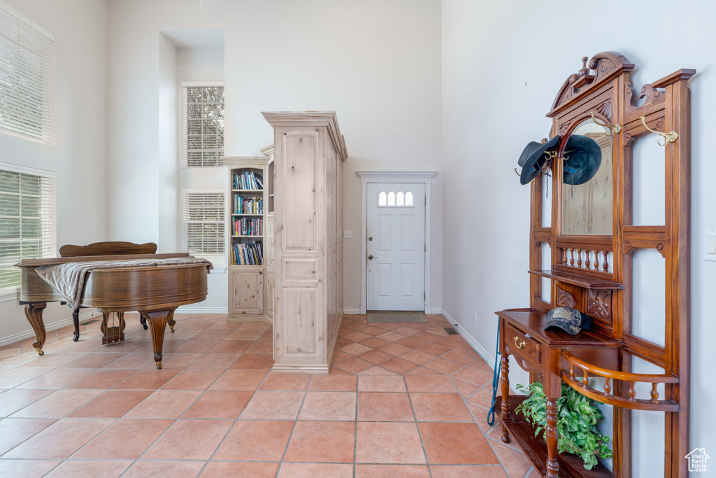 Foyer with a towering ceiling, baseboards, and light tile patterned flooring