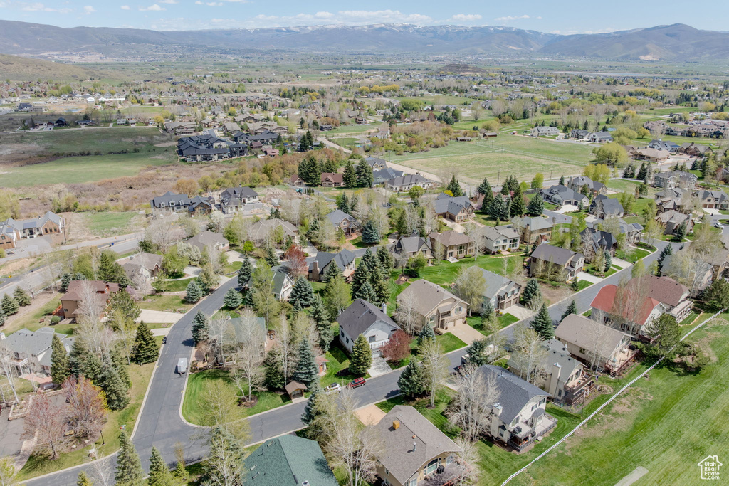 Aerial view of property and surrounding area featuring nearby suburban area and a mountain backdrop