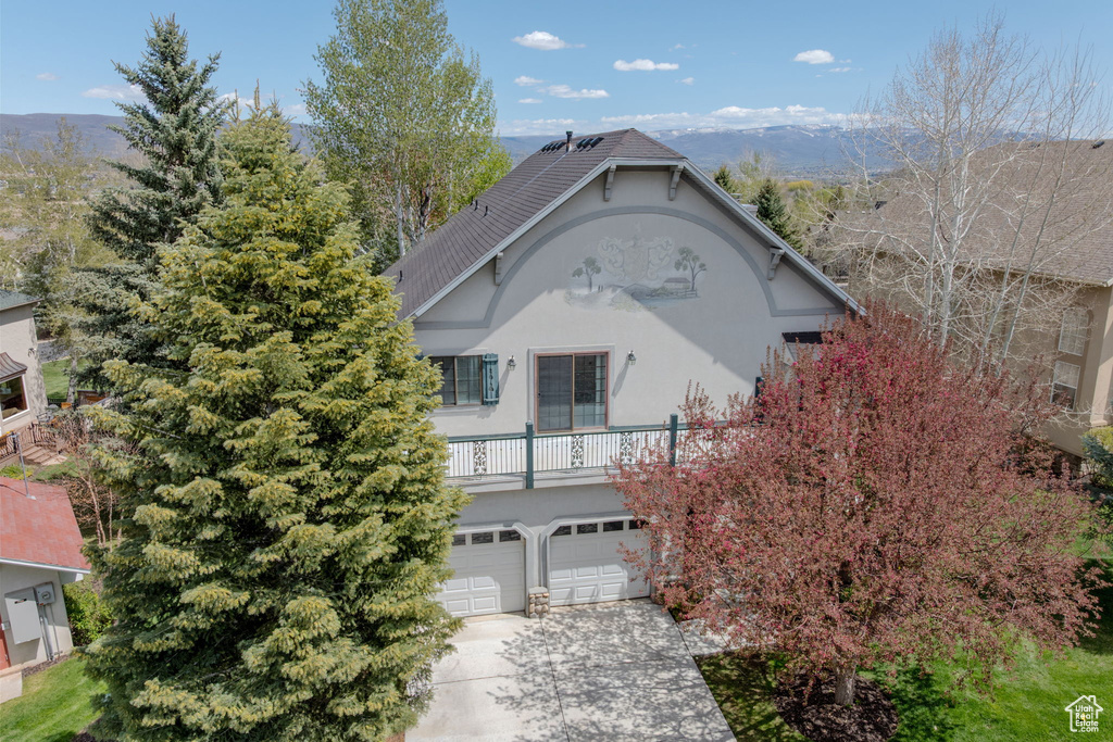 View of front facade featuring stucco siding, driveway, and a garage