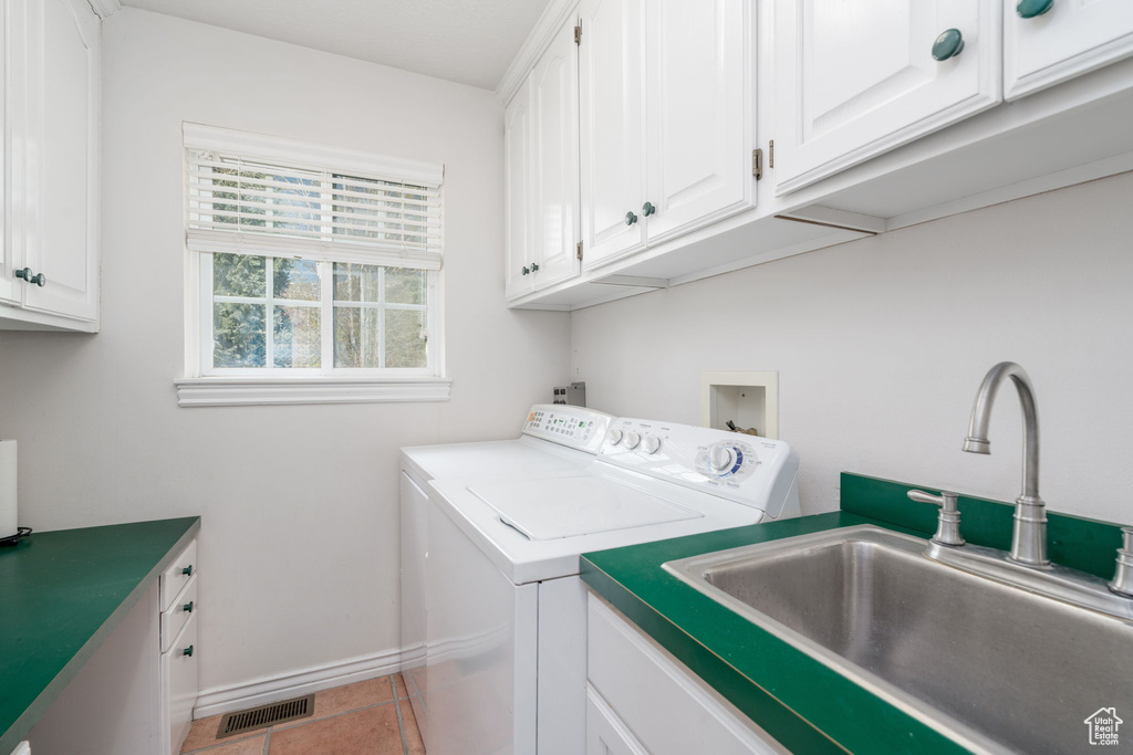 Clothes washing area featuring cabinet space, washing machine and clothes dryer, baseboards, and light tile patterned floors