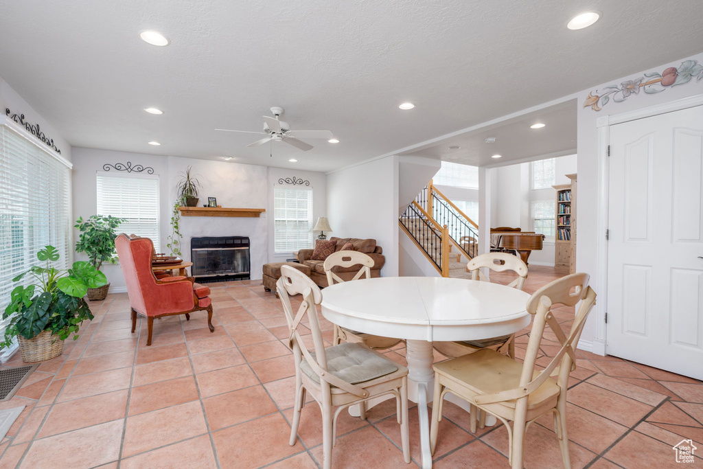 Dining room featuring recessed lighting, ceiling fan, a glass covered fireplace, and stairs
