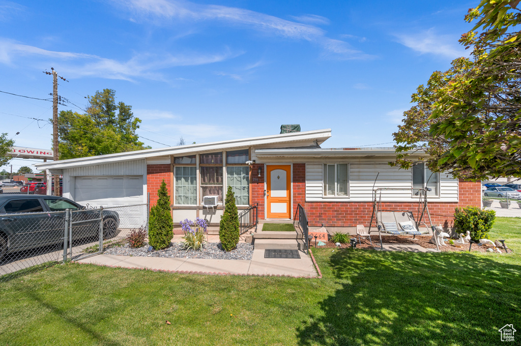 Single story home with brick siding, an attached garage, and a front lawn